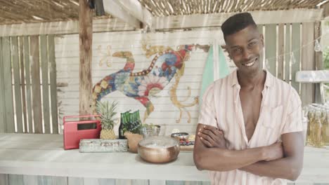 portrait of happy african american male bar owner, smiling at his beach bar, slow motion