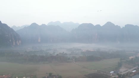 Drohnenaufnahme-Des-Nebels-Im-Tal-In-Vang-Vieng,-Der-Abenteuerhauptstadt-Von-Laos