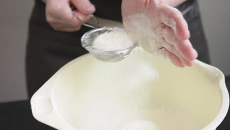 female hands sifts the flour