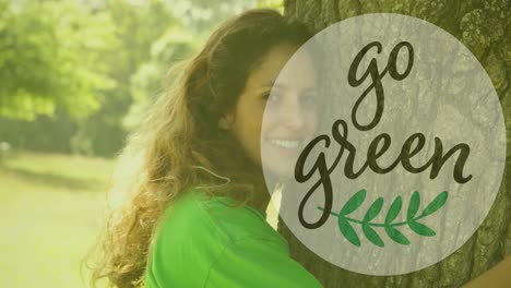 animation of go green text over caucasian woman embracing tree