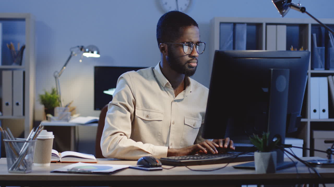 Portrait Of Man Working On The Laptop Turning His Head To The Camera And Smiling In The Office At Night