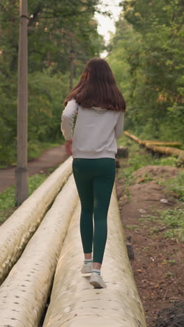 corredora femenina corre en la superficie de las tuberías en el parque. mujer se dedica a entrenar en condiciones difíciles para aumentar la resistencia y la coordinación de los movimientos