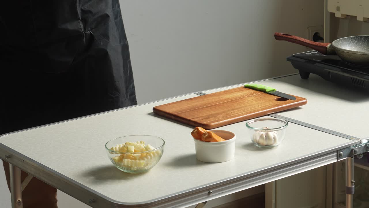 A person preparing and arranging fresh ingredients for cooking on a kitchen table