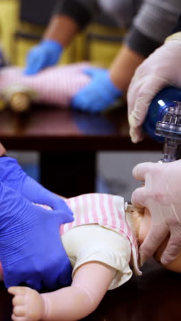 demonstrating chest compressions on medical infant dummy doll. simulator for training first aid. heart massage training. concept of medical education and practice. vertical video