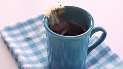 Cup-of-tea-with-tea-bag-on-wooden-table-close-up