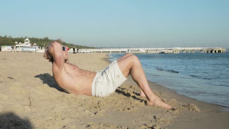 Un-Hombre-Atlético-Hace-Abdominales-En-La-Playa