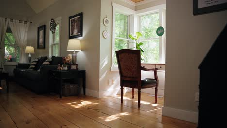 a small desk with an old chair setup in a nook in the living room, with sunlight shining through surrounding windows onto the desk