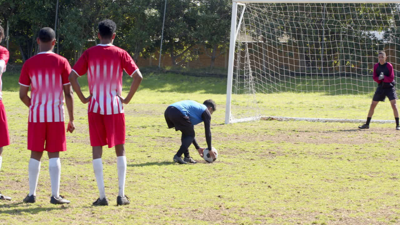 Playing soccer, player preparing to kick ball towards goal with goalkeeper ready