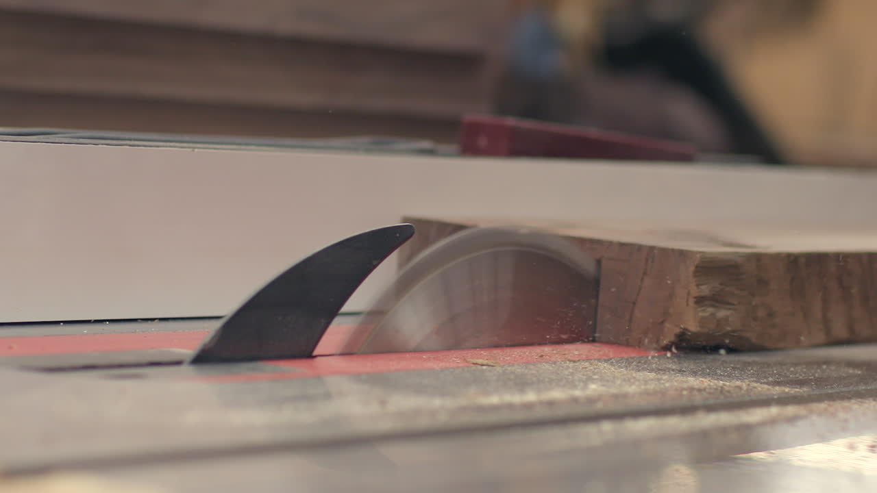 un trozo de madera se corta en dos en una sierra de mesa en cámara lenta de cerca