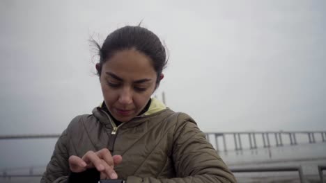 Focused-hindu-woman-setting-sport-watch-outdoor