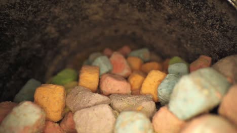 quickly pulling out of bottom of container of multi colored marshmallow pieces