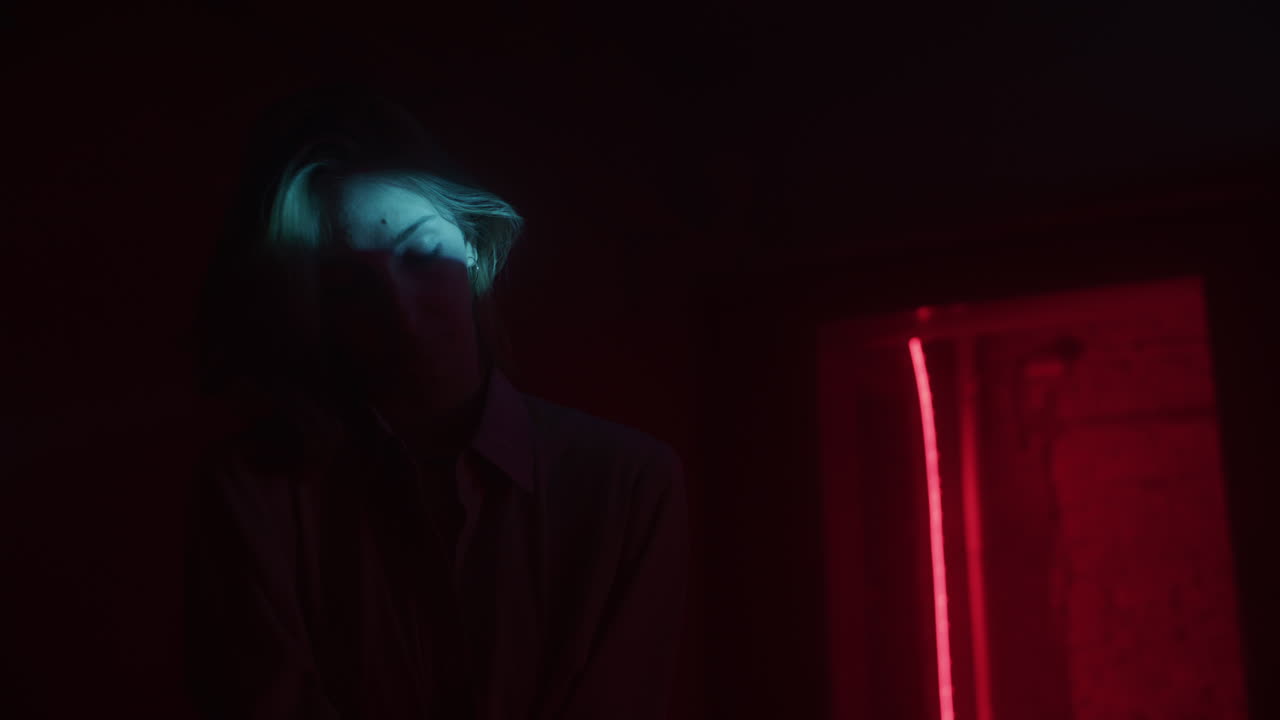 Donna in una stanza buia illuminata da luci neon