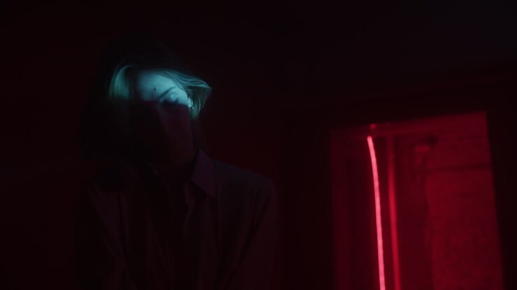 Donna in una stanza buia illuminata da luci neon