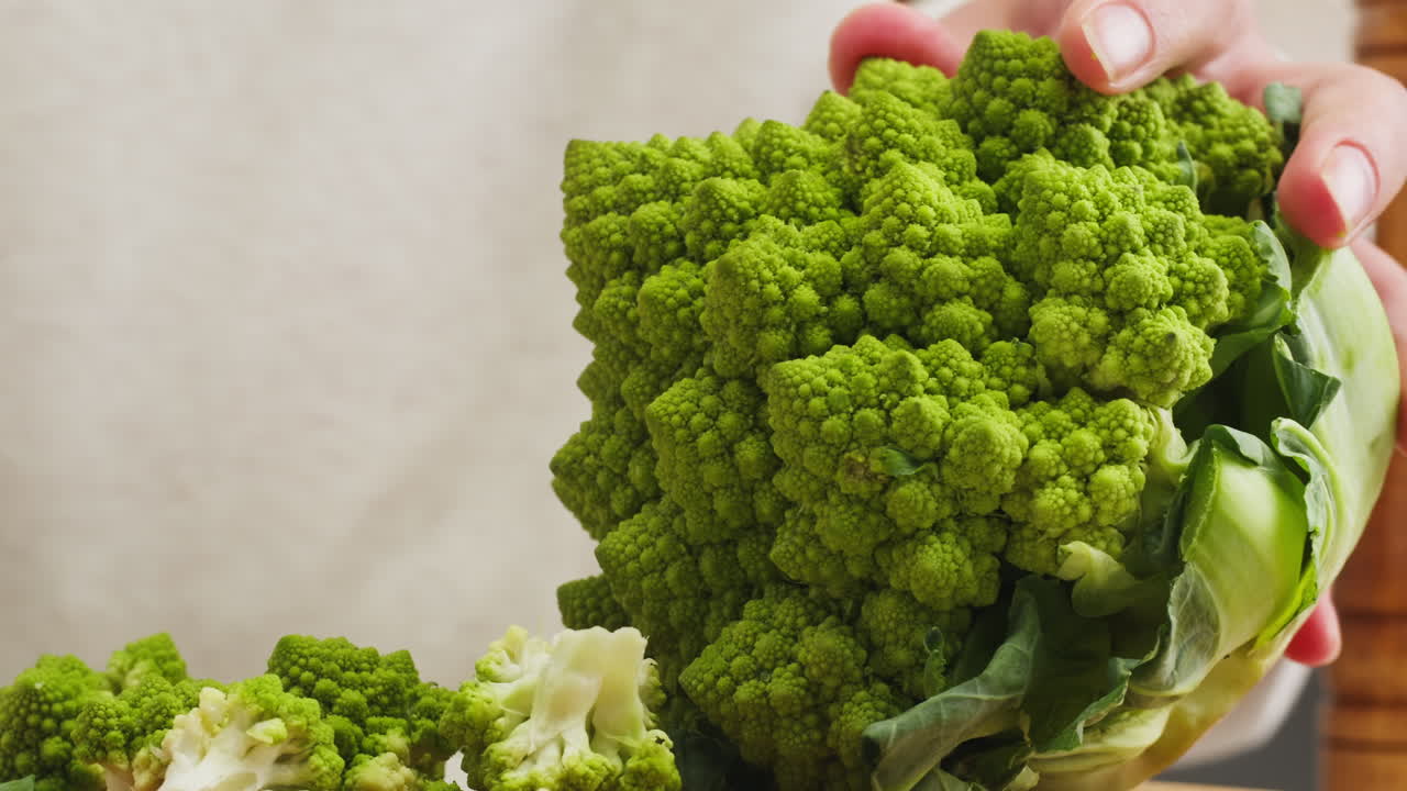 Close Up of Hands Cutting Fresh Romanesco Broccoli with a Knife