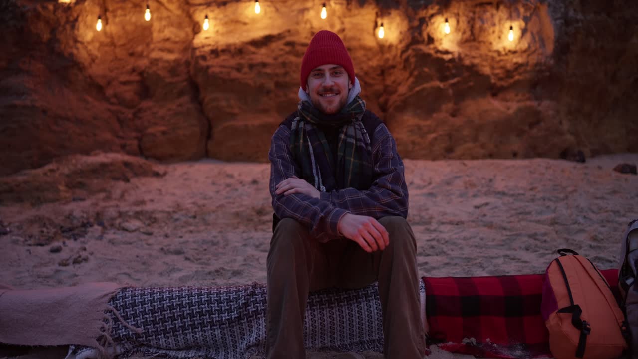 Hombre acampando en la playa de noche