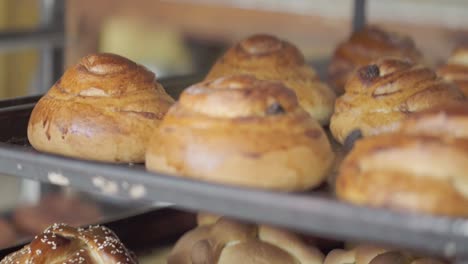 close-up of multiple trays filled with assorted baked pastries cooling on racks inside a bakery