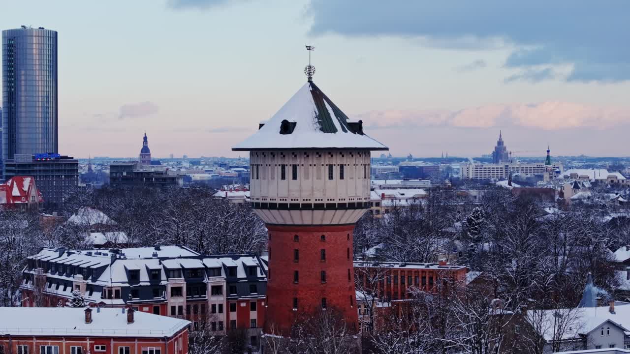 Riga’s historic water tower stands tall on snowy evening twilight, Latvia, drone