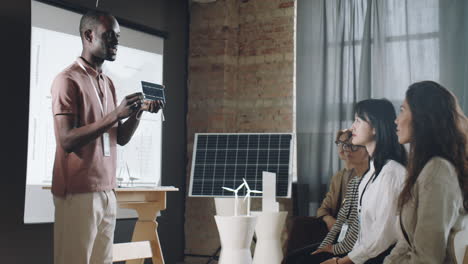 hombre afroamericano presentando cargador solar en una conferencia