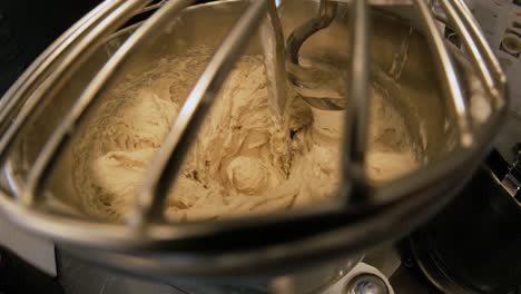 close-up of dough mixing in a professional kneader machine in kitchen of bakery or at the manufacturing. stock footage. dough making process