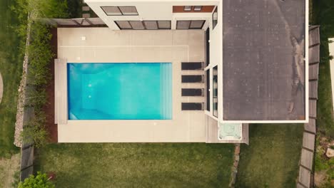 top down drone shot of a pool at a luxury home with 4 black lounge chairs