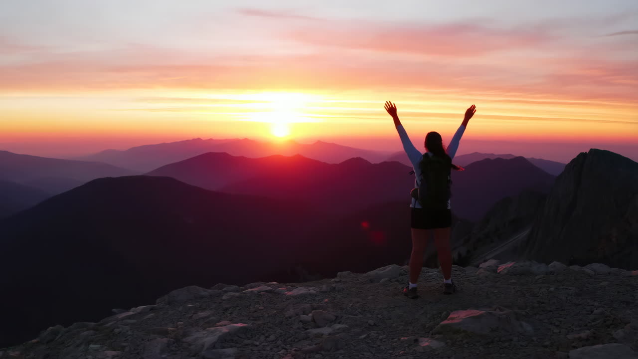 Hiker Celebrating Success on Mountain Peak at Sunset