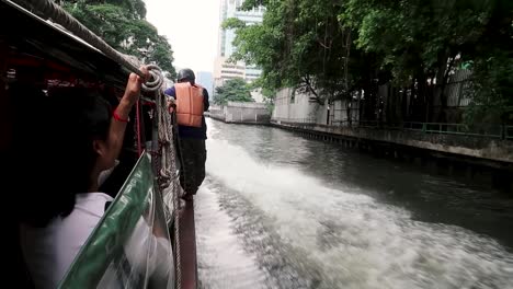 man riding on the side of a water taxi