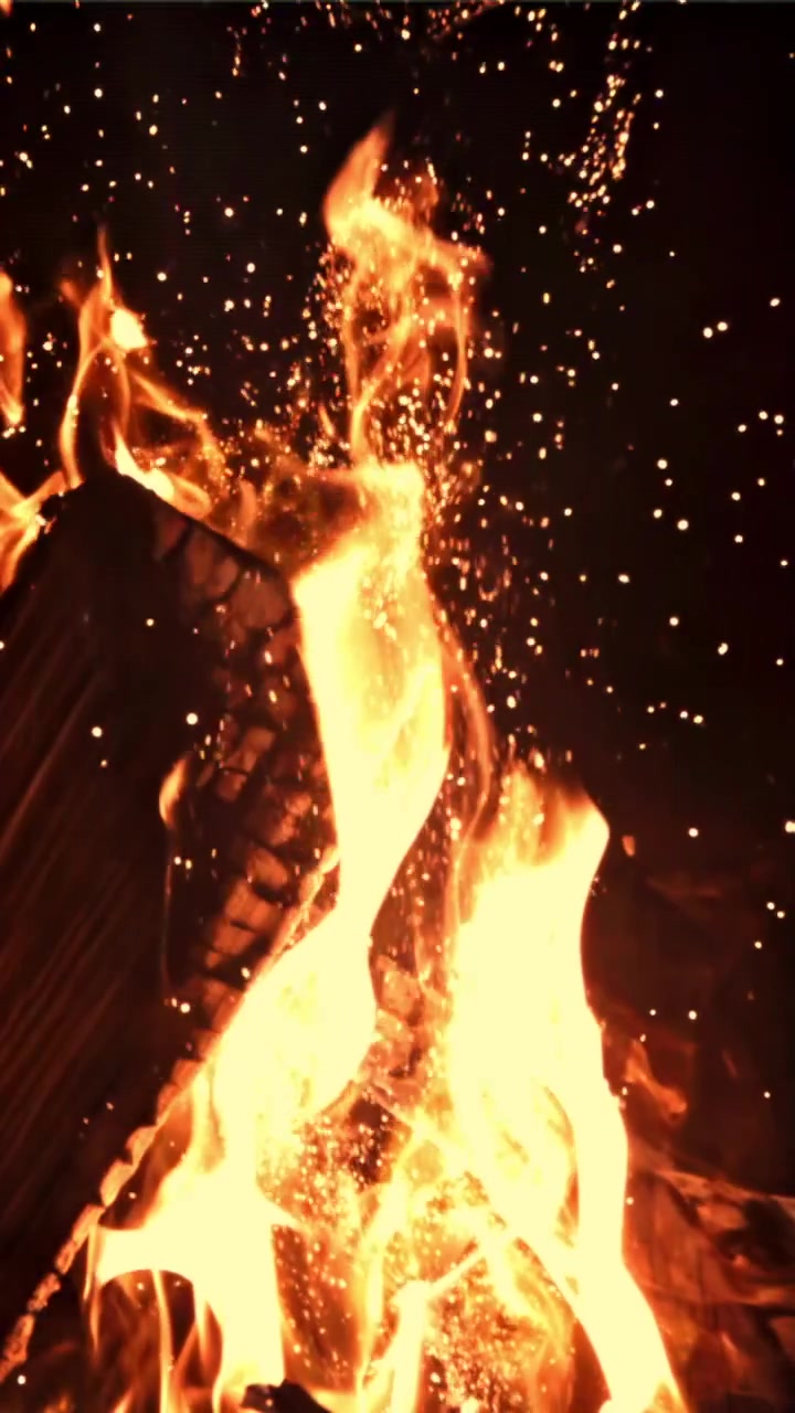 Primo piano di fiamme luminose di falò con scintille volanti di notte