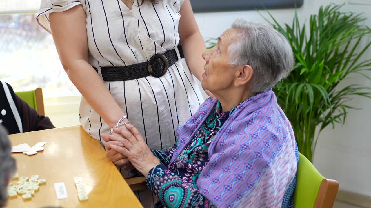 Elderly woman playing dominoes, receiving care