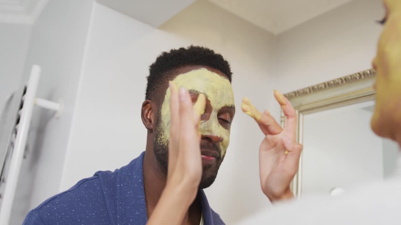 pareja feliz diversa haciendo maquillaje y mirándose el uno al otro en el baño