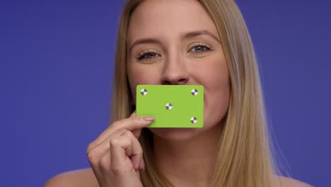 hermosa mujer sosteniendo una tarjeta en blanco delante de su boca y mirando sorprendido en la pantalla azul