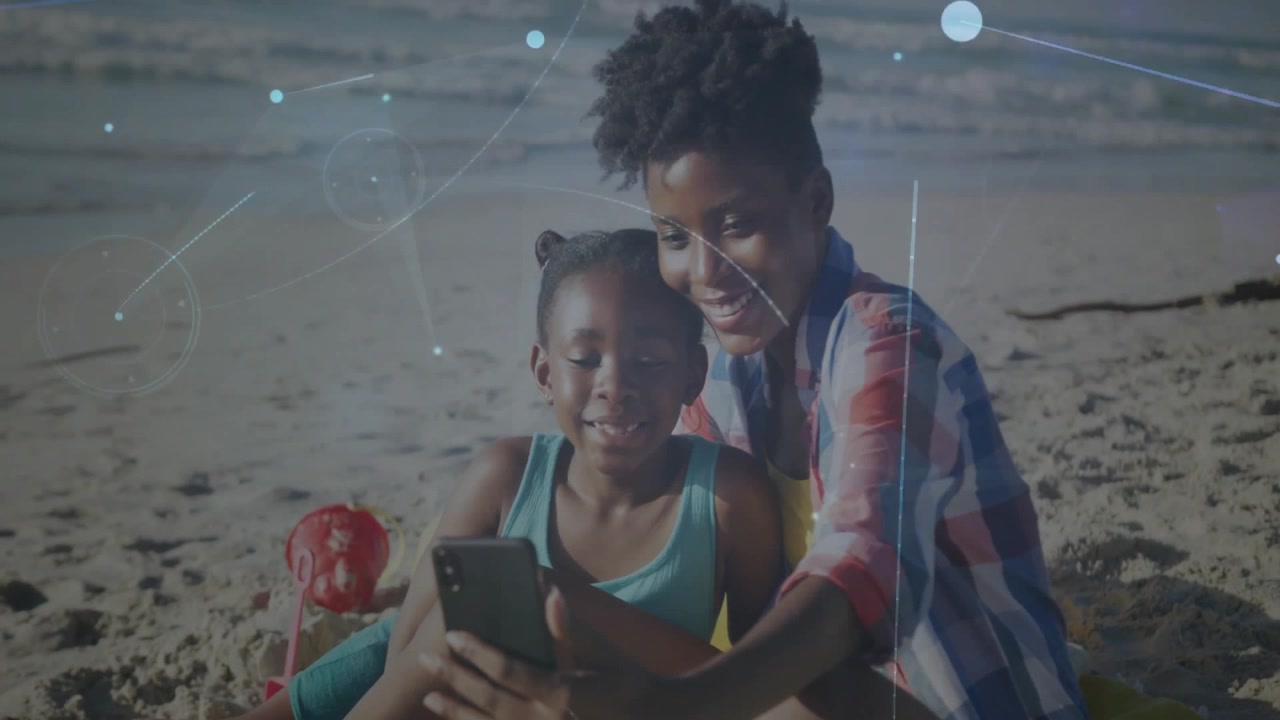 Girl tapping smartphone on beach and initiating network graphics over screen with mother guiding