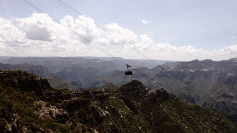 aerial view following a cable car with the mountains in the background on a sunny afternoon