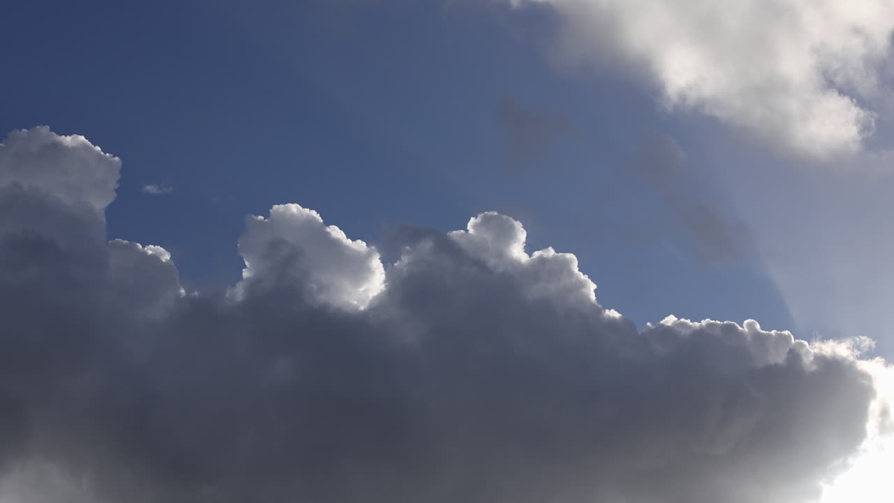 Vista verso l'alto di nuvole con bordo argentato che passano davanti al sole in un cielo blu