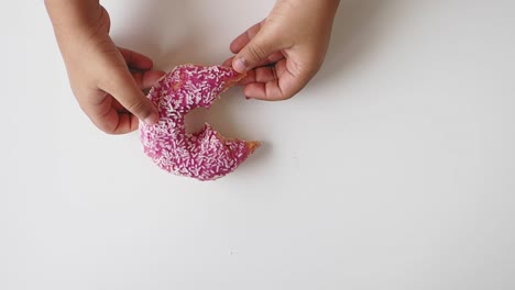 una rosquilla rosa con salpicaduras en la mano
