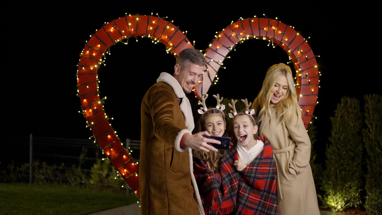A family taking a selfie in front of a heart shaped light display