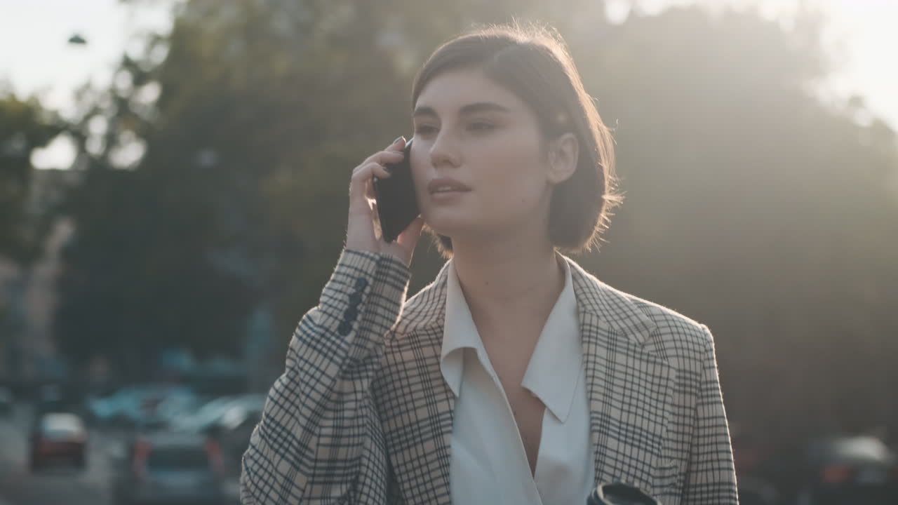 스타일리시한 여성이 야외에서 비즈니스 통화를 하고 있습니다.