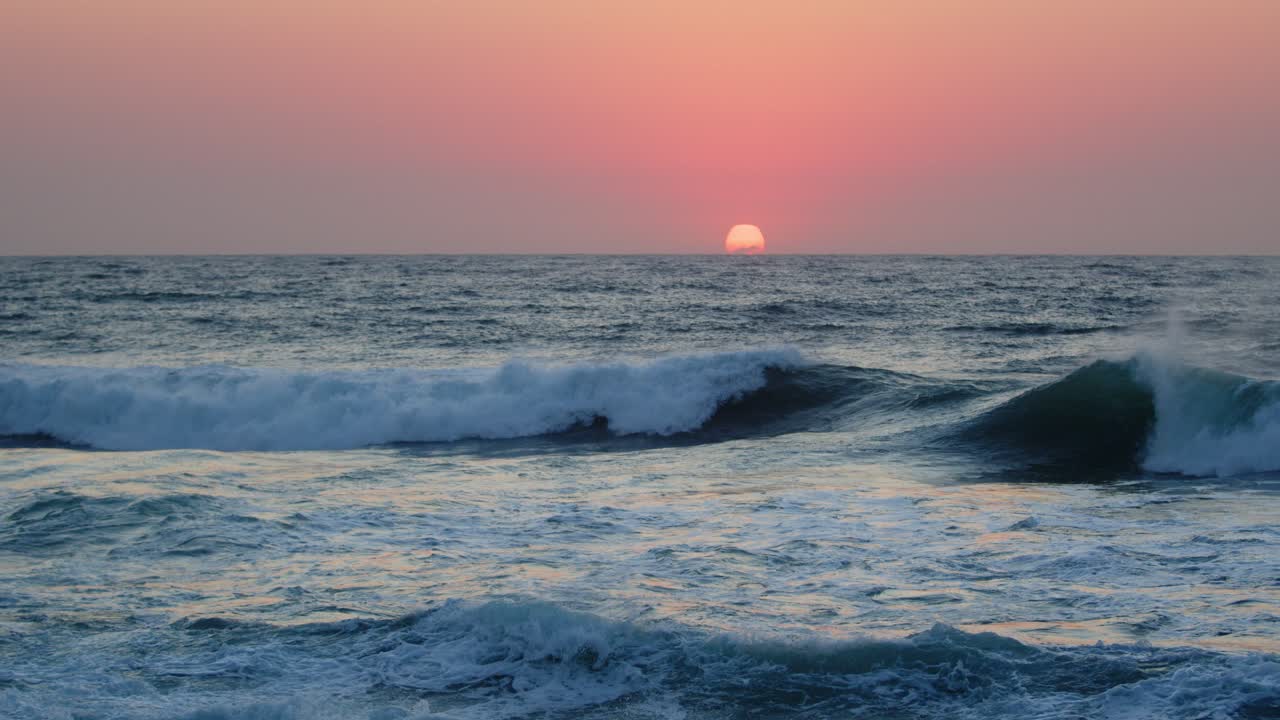 amanecer rosa dramático en cámara lenta reflejado sobre olas rompientes en la playa, durban, kwazulu-natal