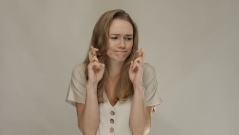 Young-happy-woman-crossing-her-fingers-and-wishing-for-good-luck