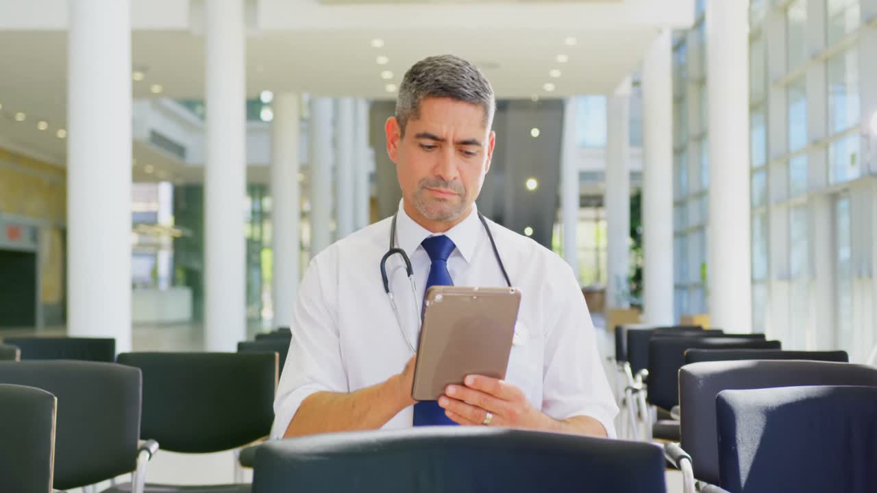 médico caucásico que sostiene una tableta digital en el vestíbulo de la oficina 4k