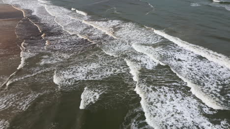 aerial shot of rhythmic waves washing ashore in denmark