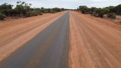 Drone-flying-over-a-deserted-country-road-at-low-altitude