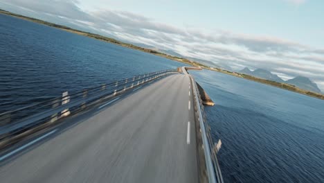 winding road bridge over nordic water in fast flying over fpv drone shot