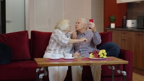 elderly couple taking a selfie together on a sofa