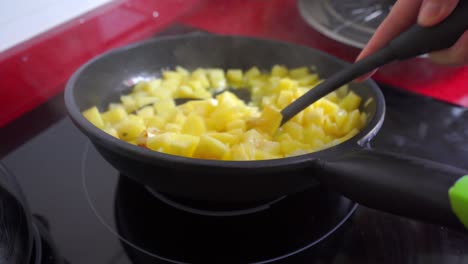 stirring the onion and potatoes in a frying pan