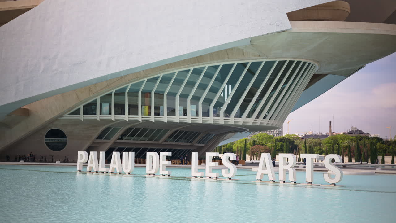 Valencia, Spain - May 28, 2025: White Palau de les Arts letters floating on the pool with the building's sweeping forms behind