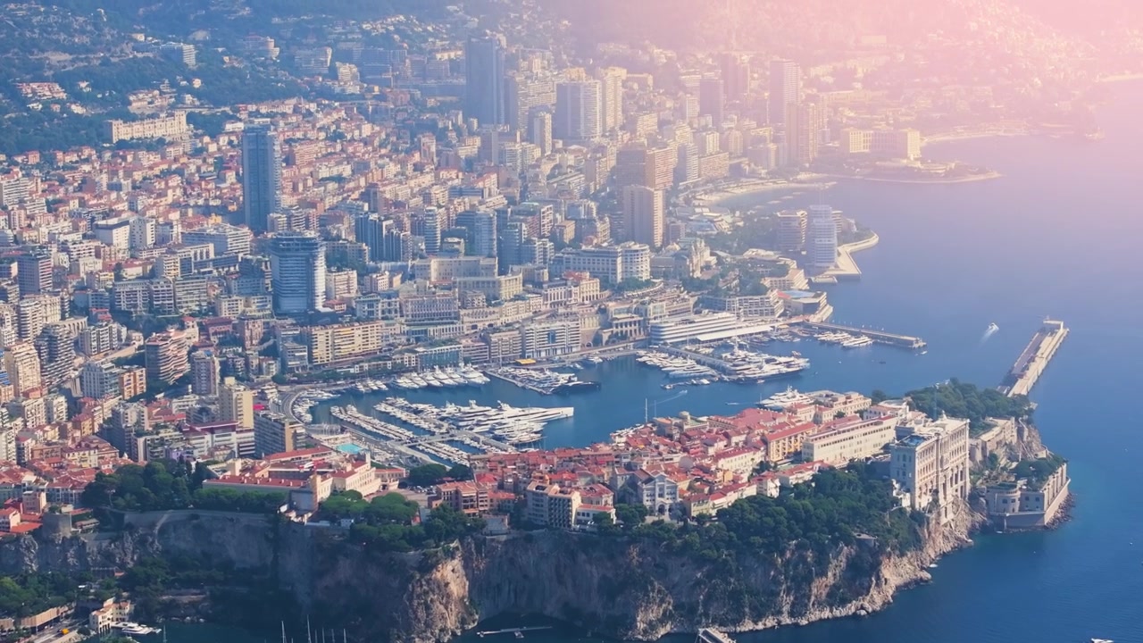 Il video mostra il porto di Monaco con yacht di lusso ed edifici lungo la costa. Il filmato evidenzia l'attività diurna e la vivace vita cittadina di questa famosa località.