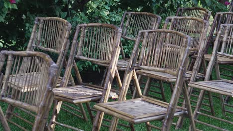 a row of bamboo chairs are lined up in a grassy field