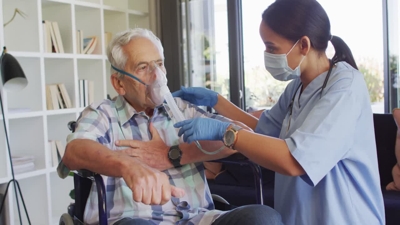 Video of biracial female doctor in face mask keeping oxygen to caucasian senior man