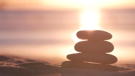 stack of pebble stones, sandy ocean beach, sunset sky. rock balancing by water.