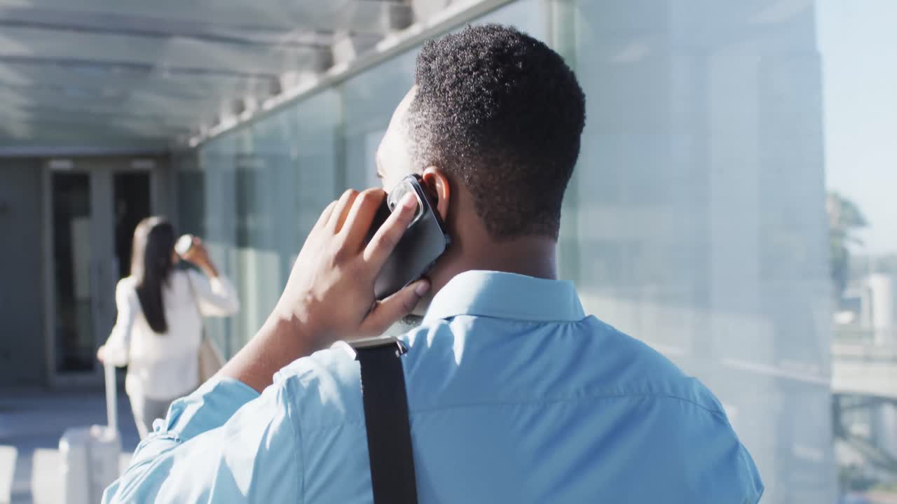 Video of back view of african american man walking and using smartphone